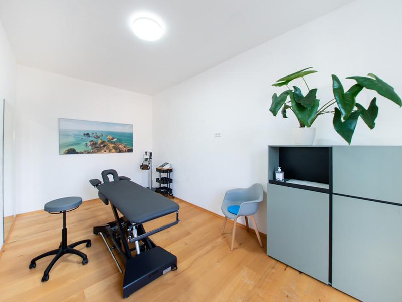 Behandlungsraum mit Therapieliege und Rollhocker